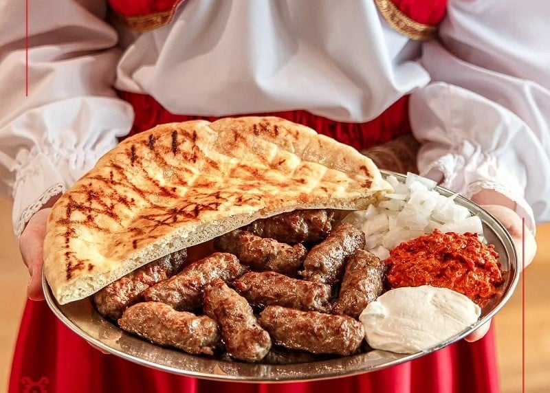 الطبق الوطني البوسني تشيفابتشيتشي مع اللحم المشوي والخبز الصومون والصلصات التقليدية