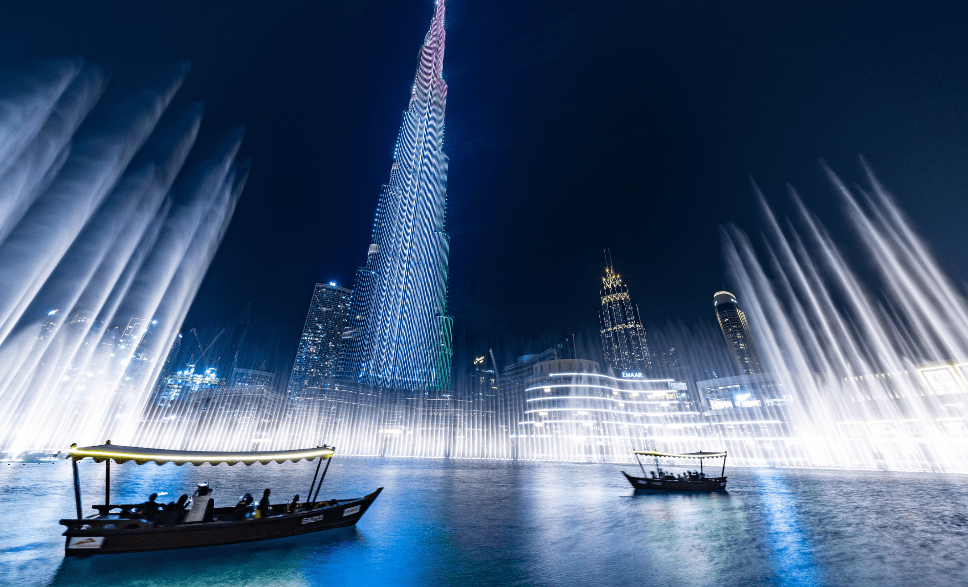 "برج خليفة في دبي يظهر في أجمل أوقات الغروب مع إطلالة على نافورة دبي الراقصة ودبي مول في الخلفية"